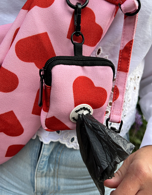 Détail du sac à crottes et du tissu cœur rouge du sac Amore pour petit chien