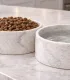 Détail des gamelles en marbre de Carrare avec croquettes et eau.