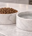Détail des gamelles en marbre de Carrare avec croquettes et eau.