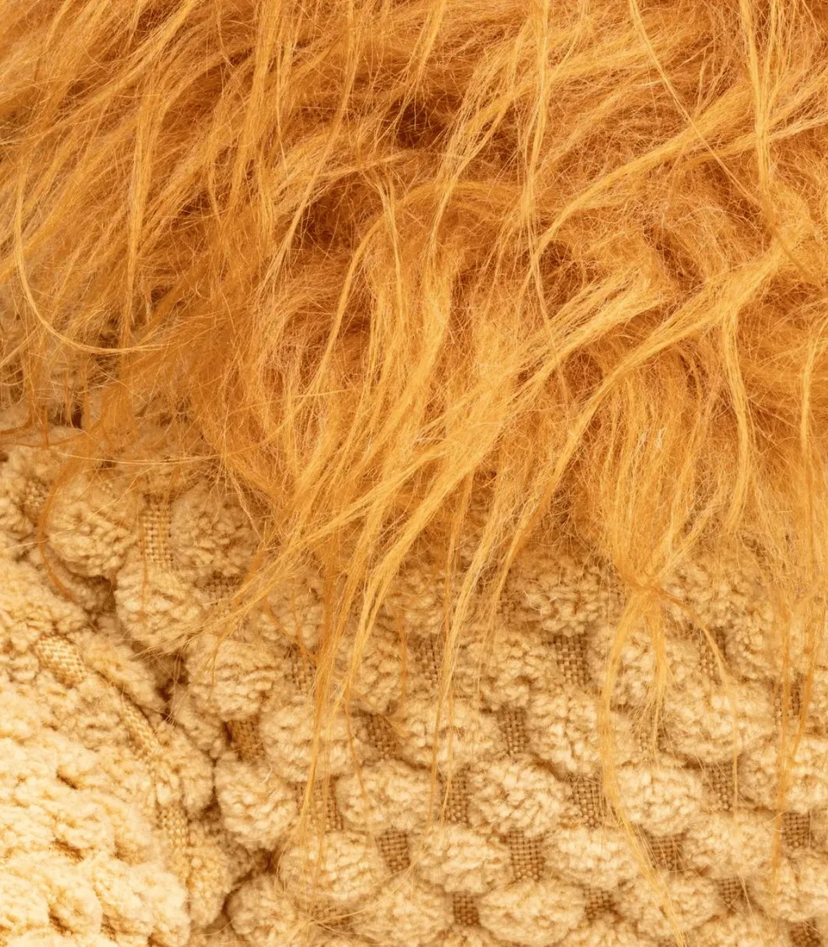 Gros plan sur la crinière orange et le tricot gaufré de la peluche lion