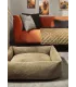 Panier pour chien vert olive Tudor installé dans un salon moderne devant un canapé orange