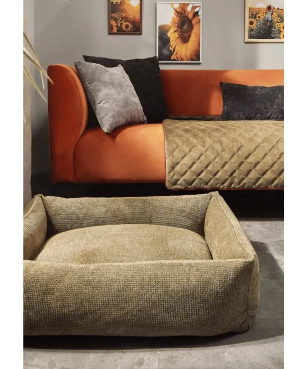 Panier pour chien vert olive Tudor installé dans un salon moderne devant un canapé orange