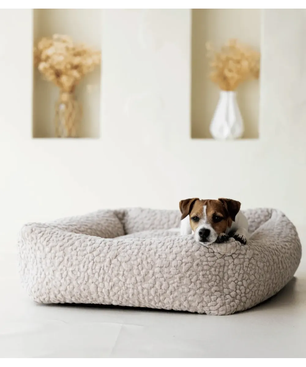 Petit chien installé dans un lit pour chien Bellagio beige, décor de fleurs séchées