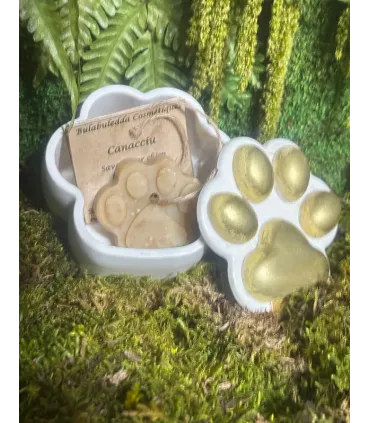 Écrin patte ouvert laissant voir son savon Canacciu artisanal pour chien et son emballage kraft, posé sur de la mousse